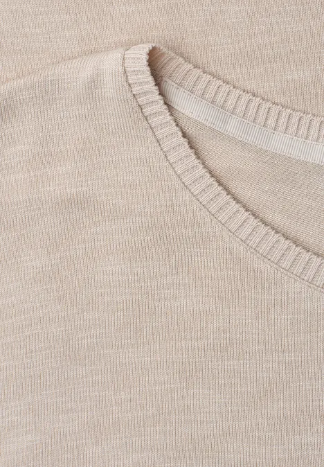 Nahaufnahme eines beigen Strickpullover-Ausschnitts.