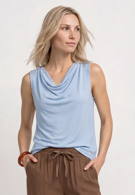 Silk-Look Top mit Wasserfall-Ausschnitt cashmere blue Frau mit hellblauem ärmellosem Top und braunen Hosen vor hellem Hintergrund.