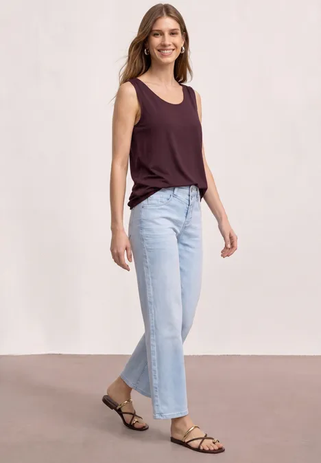 Top aus Jersey mit Elastiksaum rustic rouge Frau in ärmellosem bordeauxfarbenen Top, weiten hellen Jeans und schlichten Riemchensandalen.