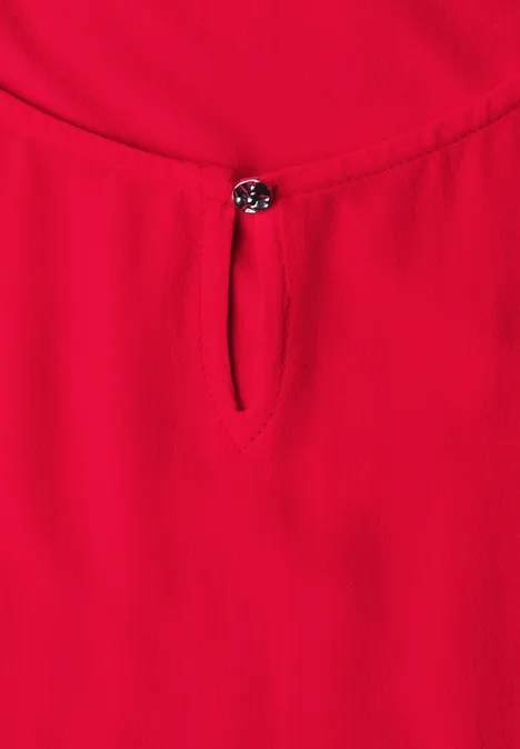 Rotes Top mit Rundhalsausschnitt und kleinem Knopfdetail vorne.