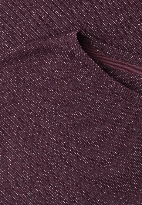 Chemise dropped shoulder avec détails scintillants rustic rouge Gros plan d’un tissu tricoté bordeaux pailleté avec une poche appliquée.