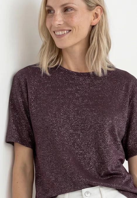 Chemise dropped shoulder avec détails scintillants rustic rouge Femme en T-shirt violet pailleté souriant devant un fond clair.