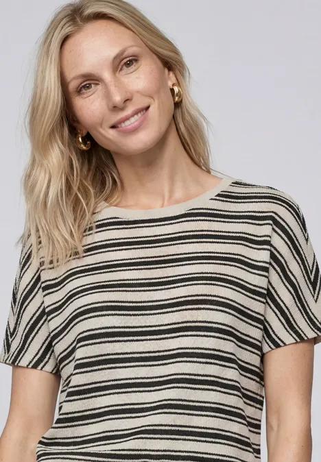 Shirt in Strick-Optik mit Rundhals Black Frau trägt kurzärmliges gestreiftes Oberteil in Schwarz und Weiß.