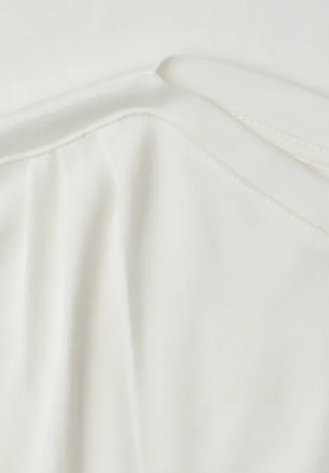 Shirt met overhangende schouders en rimpels off white Close-up van een wit kledingstuk met ronde hals en subtiele plooien