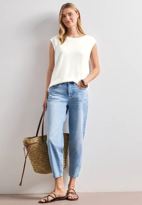 Shirt mit Rundhals und Rippdetails off white Frau in weißem Oberteil, hellen Jeans und schwarzen Sandalen trägt eine geflochtene Strohtasche.