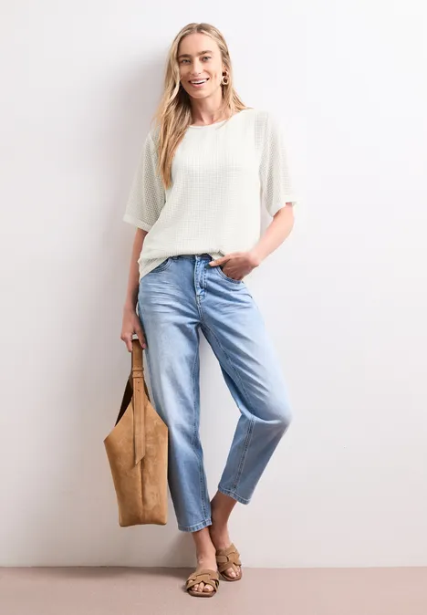 2-in-1 Shirt aus Mesh mit U-Boot-Ausschnitt off white Frau in weißem Oberteil und hellblauen Jeans, trägt eine Tasche und Sandalen, vor weißem Hintergrund.