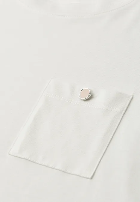 Weißes T-Shirt mit Brusttasche und kleinem rundem Anstecker in Rosé an der Tasche vorne.