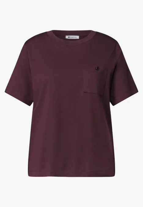 Ein kastiges, kurzärmeliges T-Shirt in dunklem Aubergine mit Brusttasche.