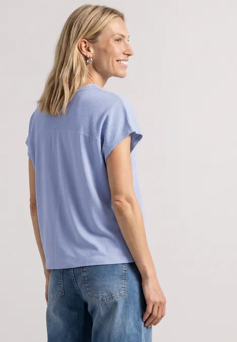 Dropped Shoulder Shirt mit Strukturmix cashmere blue Eine Frau mit blonden Haaren trägt ein hellblaues T-Shirt und Jeans, im Profil, vor neutralem Hintergrund.