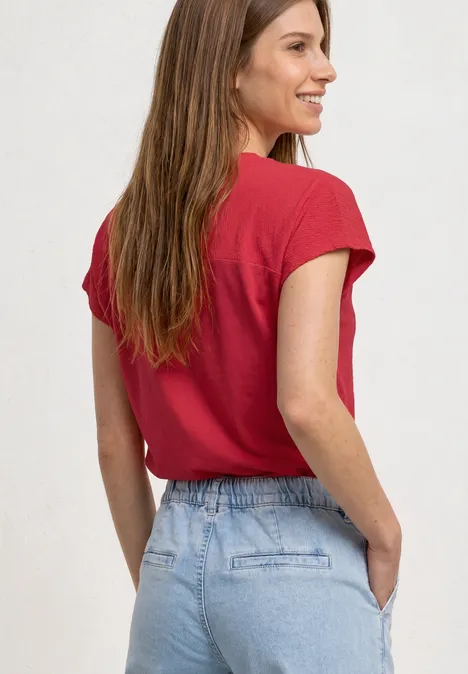 Dropped Shoulder Shirt mit Strukturmix salsa red Frau in rotem T-Shirt und Jeans von hinten, Hände in den Taschen.