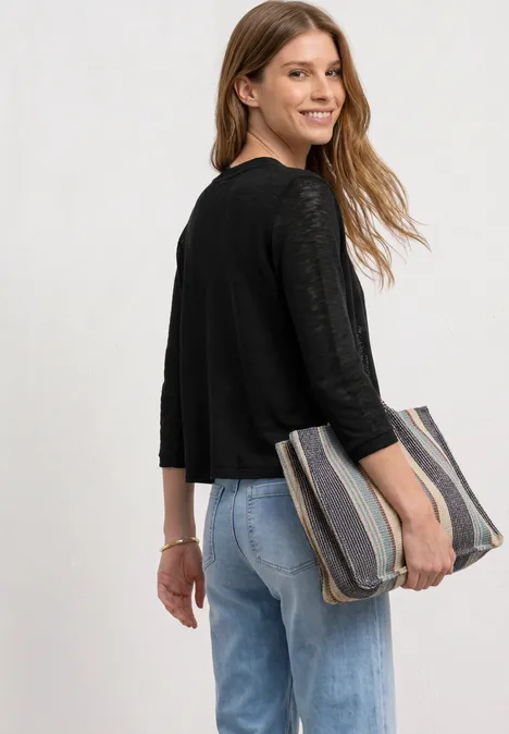 Jack met 3/4 mouwen in een open pasvorm Black Vrouw in zwart shirt en blauwe jeans, met een gestreepte clutch onder haar arm.