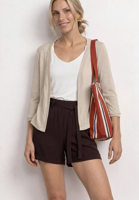 3/4-Arm Jacke in offener Passform clay sand Frau trägt weißen Top, beigen Cardigan, braune Shorts und eine gestreifte Tasche.