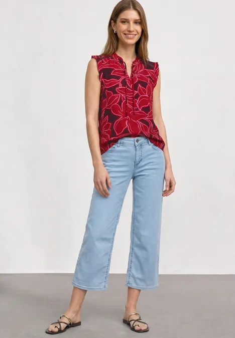 Top mit Strukturmix und Crochet-Details salsa red Model trägt rote ärmellose Bluse mit Blumenmuster, hellblaue Culotte-Jeans und schwarze Sandalen vor weißem Hintergrund.