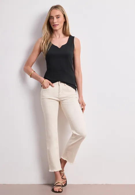 Basic Top mit Herzausschnitt Black Frau in schwarzem Top und weißen Schlaghosen steht lässig in Sandalen vor weißer Wand.