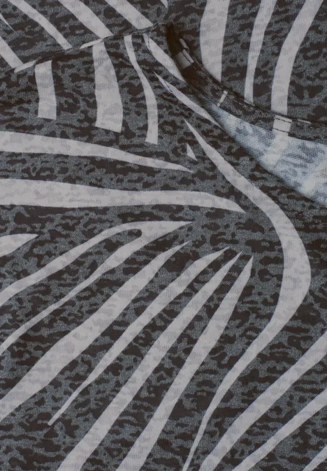 Close-up van een stof met een abstract zebradessin in grijs- en wittinten.