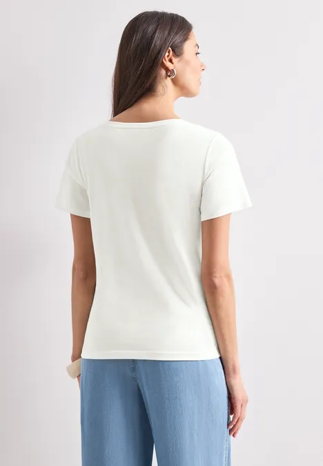 T-Shirt mit Rundhals und Artwork off white Rückenansicht einer Frau im weißen T-Shirt und hellblauer Hose vor neutralem Hintergrund.