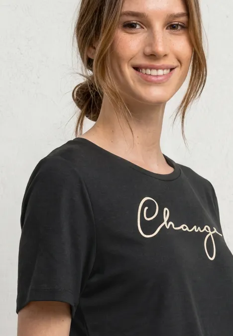 Shirt met ronde hals en Wording Artwork Black Portret van een vrouw met een zwart t-shirt voor een lichte achtergrond.