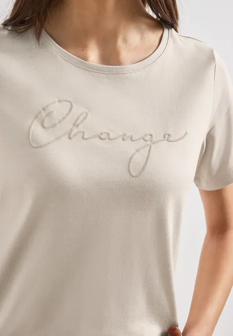 T-shirt à col rond avec wording artwork clay sand T-shirt beige pour femme avec l'inscription 'Change' en écriture cursive élégante.