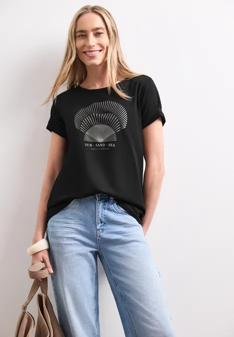 Shirt met ronde hals en foliedetails Black Vrouw draagt zwart bedrukt T-shirt, lichtblauwe jeans en houdt een bruine tas vast.