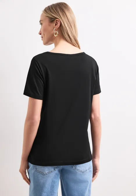 Shirt met ronde hals en foliedetails Black Achteraanzicht van een vrouw met blond haar, een zwart T-shirt en een blauwe spijkerbroek.
