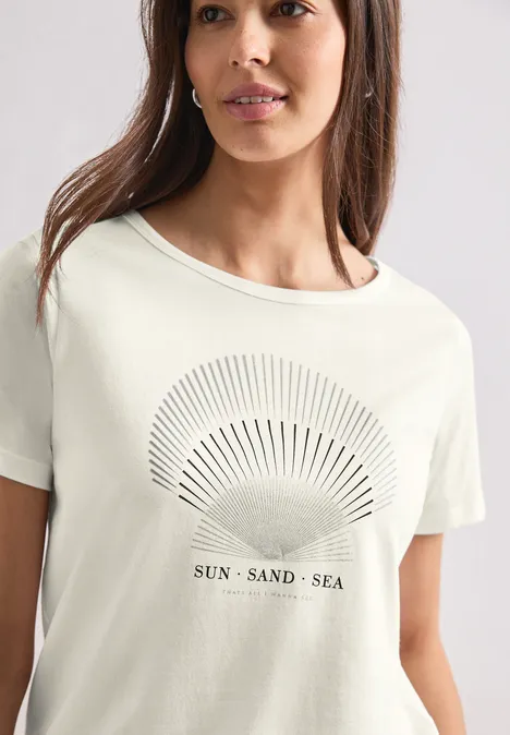 T-Shirt mit Rundhals und Foliendetails off white Frau trägt helles T-Shirt mit Sonnen- und Meeresmotiv und Schriftzug 'SUN SAND SEA'.