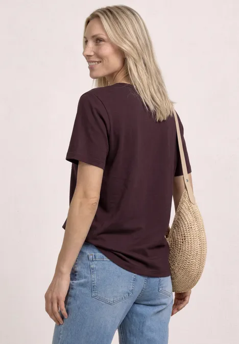 Vrouw van achter in donker T-shirt, blauwe jeans en strozak over schouder.