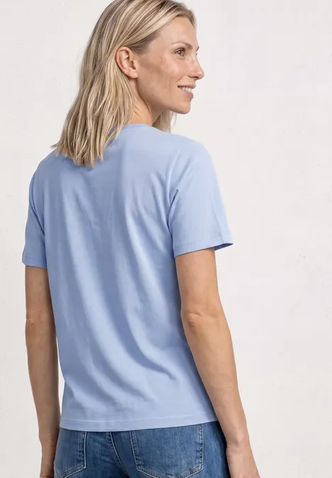 T-Shirt mit Rundhals und Embroidery Detail cashmere blue Rückansicht einer Person in hellblauem T-Shirt und Jeans, vor neutralem Hintergrund.