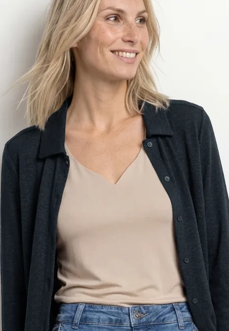Leichte Langam Jacke in Leinen-Optik shadowed navy Schulterlanges blondes Haar, beige Top mit V-Ausschnitt und schwarze Strickjacke vor hellem Hintergrund.