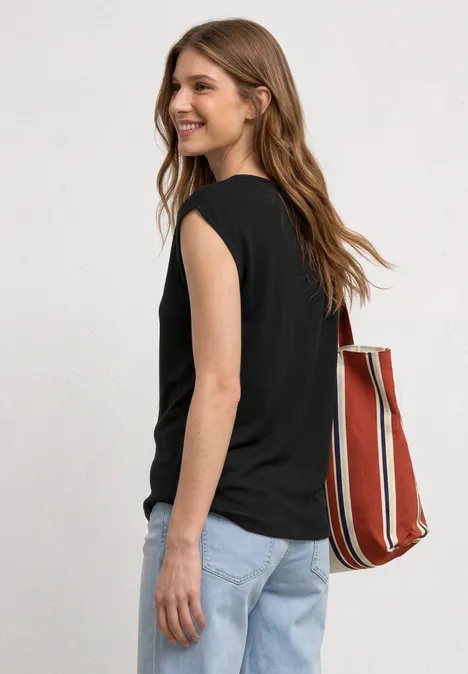 Basic shirt met boothals Black Een vrouw gezien van achteren met zwart mouwloos topje, lichte spijkerbroek en rood-wit gestreepte tas.
