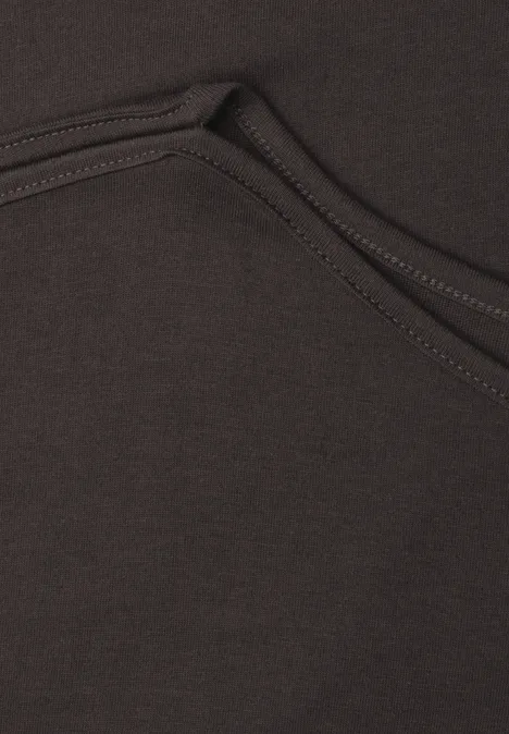 Gros plan sur la couture et la poche d’un sweat à capuche marron.