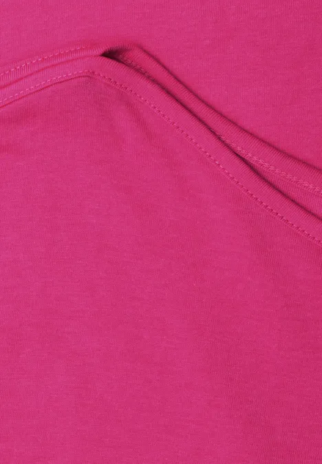 Gros plan sur un tissu rose vif avec poche cousue et surpiqûre apparente.