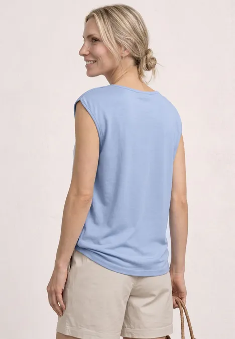 Vrouw van achteren met lichtblauw mouwloos shirt en beige short, ze draagt een gevlochten tas.