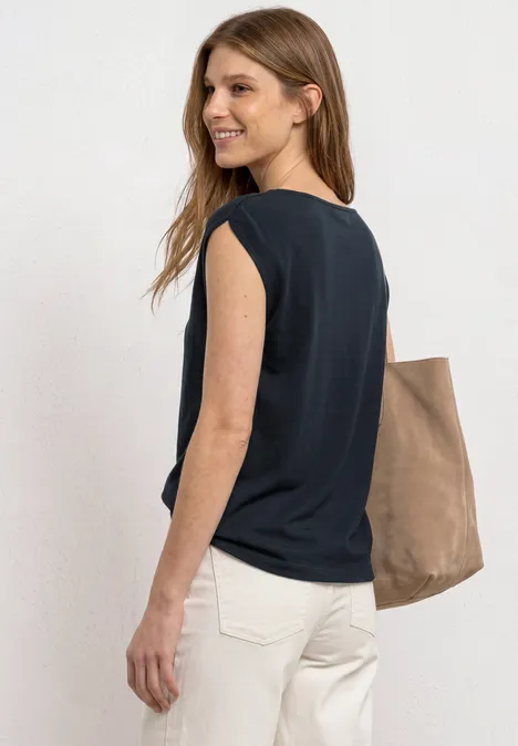 Basic Shirt mit U-Boot-Ausschnitt shadowed navy Seitliche Aufnahme einer Frau mit schwarzem ärmellosem Top, weißen Hosen und brauner Tasche.