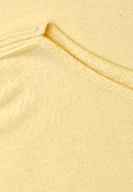 Close-up van een geel kledingstuk met ronde hals en zichtbare naden.