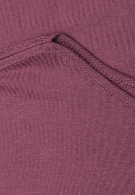 Gros plan sur un tissu violet bordeaux avec couture et plis de poche.