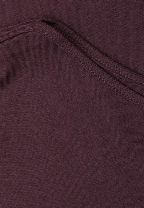 Basic shirt met boothals rustic rouge Close-up van een bordeauxrode stoffen zak met zichtbare naad.