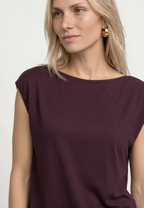 Basic shirt met boothals rustic rouge Blonde vrouw met donkerrood topje voor een witte achtergrond.