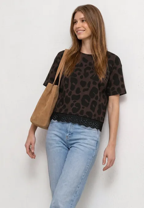 T-Shirt mit Rundhals und Spitze molten earth Frau vor weißem Hintergrund in gemustertem Kurzarmshirt, hellen Jeans und brauner Tasche.