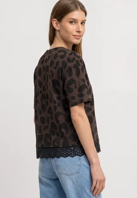 T-Shirt mit Rundhals und Spitze molten earth Eine Frau steht im Profil und trägt eine braune Leo-Tunika mit kurzen Ärmeln und hellblaue Jeans.