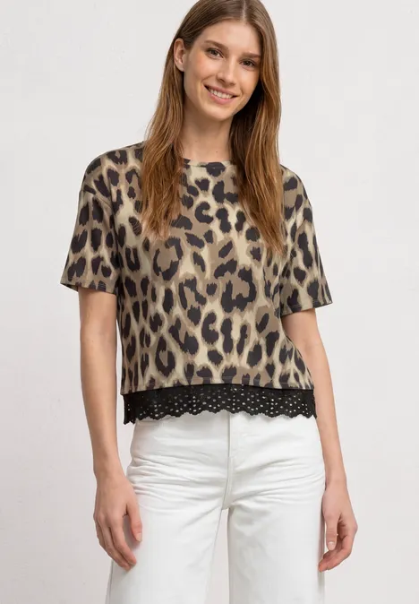 T-Shirt mit Rundhals und Spitze timeless beige Frau trägt beige-schwarzes Leopardenmuster-T-Shirt mit Spitzenbesatz am Saum und weiße Hose.
