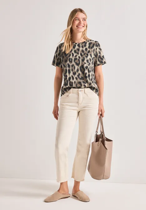 Frau in Leoparden-Print-T-Shirt, heller Cropped-Hose, beigen Slippern und einer passenden Tasche.
