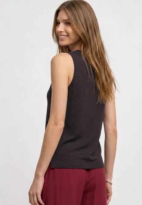 Top mit U-Boot-Ausschnitt und Schulterdetail espresso brown Frau von hinten in schwarzem Tanktop und roter Hose vor hellem Hintergrund.