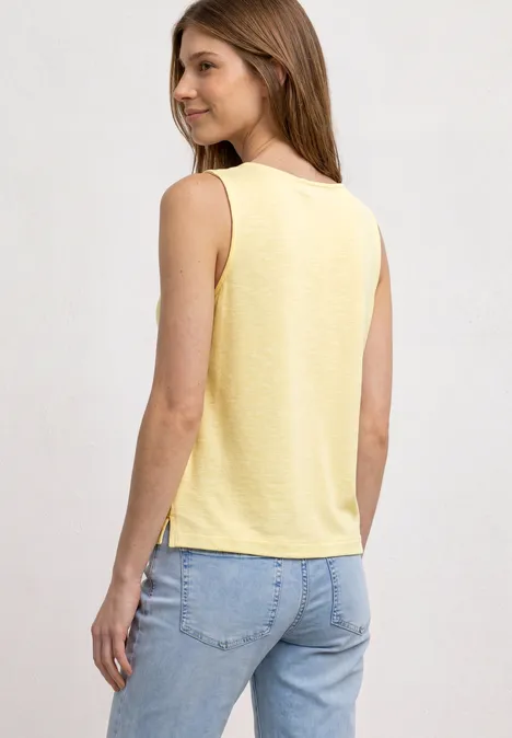 Top mit U-Boot-Ausschnitt und Schulterdetail soft yellow Eine Frau von hinten in einem gelben ärmellosen Top und hellblauen Jeans.