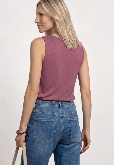 Top mit U-Boot-Ausschnitt und Schulterdetail dark clouded blush Frau von hinten in ärmellosem rosa Top und blauer Jeans.