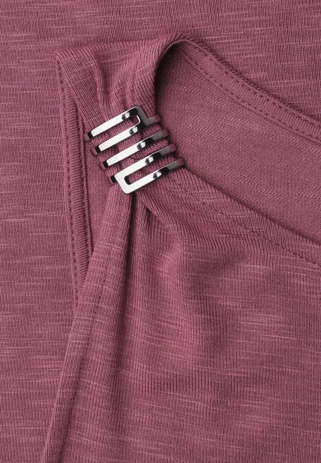Top mit U-Boot-Ausschnitt und Schulterdetail dark clouded blush Nahaufnahme eines rötlich-lila Oberteils mit einer silbernen Zierschließe am Ausschnitt.