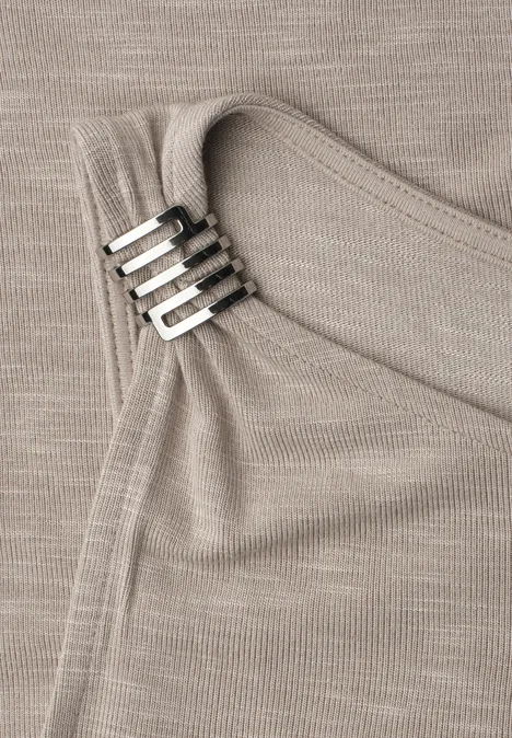 Nahaufnahme eines beigen Stricktops mit silbernen Rechteck-Clips am Träger und feiner Rippstruktur.