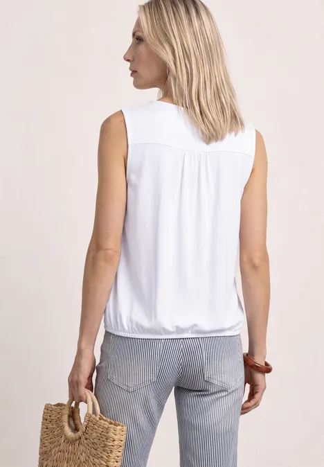 Top aus Jersey mit Elastiksaum White Frau von hinten in ärmelloser weißer Bluse und Jeans, trägt handgeflochtene Tasche.