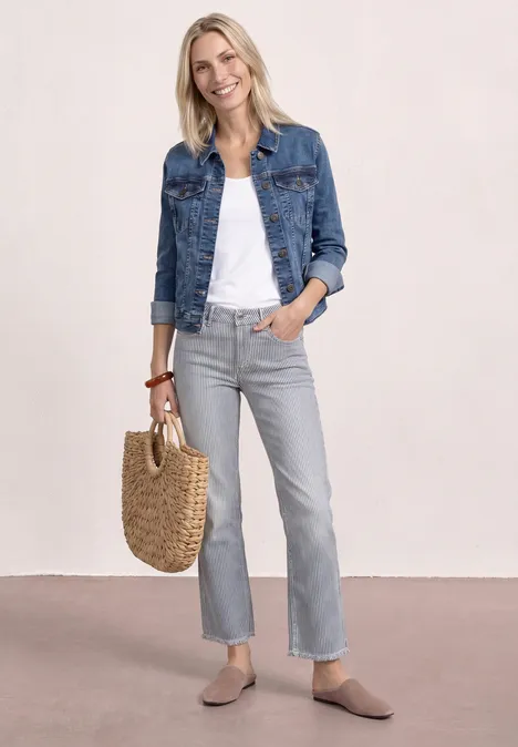Top aus Jersey mit Elastiksaum White Frau in Jeansjacke, weißem Top, grauen Jeans, beigen Slippern und geflochtener Tasche.