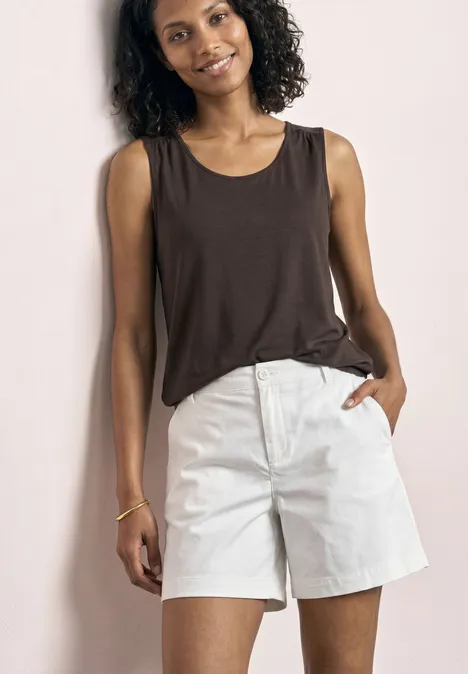 Top aus Jersey mit Elastiksaum espresso brown Eine junge Frau mit lockigem Haar trägt ein braunes Tanktop und weiße Shorts und lächelt.