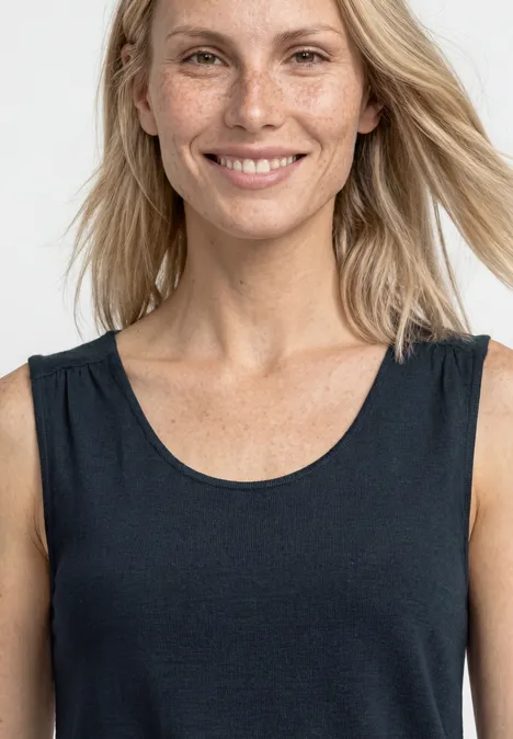 Blonde Frau mit lockeren Haaren trägt ein ärmelloses schwarzes Top, Schultern und Hals sichtbar.